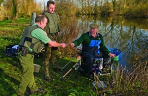 An angler hands his rod licence over for inspection