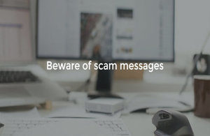 Blurred image of computer with the words 'Beware of scam messages' in white