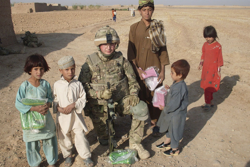 Private Marshall, A Company, 1st Battalion The Yorkshire Regiment, with Afghan children who have been given wellington boots for Eid  