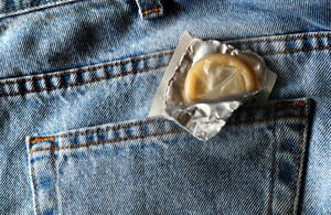 A condom sticking out of the back pocket of a pair of jeans.