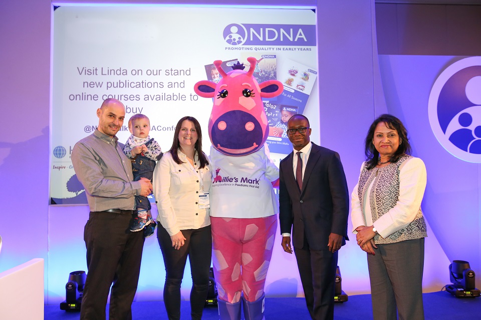 Mr and Mrs Thompson with son Leo, Millie the giraffe, Childcare Minister Sam Gyimah and National Day Nurseries Association Chief Executive Purnima Tanuku