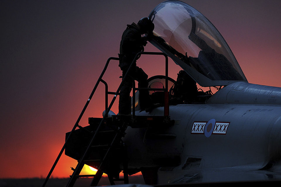 An RAF Typhoon pilot enters his cockpit as the sun sets over Gioia del Colle, southern Italy