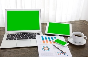 laptop, tablet, phone, coffee cup and financial documents on table