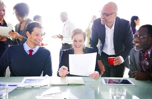 business colleagues reviewing paperwork with busy office background