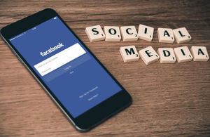 Image of a smartphone logging into Facebook with Scrabble letters spelling out social media