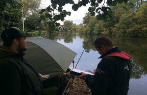 Environment Agency fisheries enforcement officer checks an angler's rod licence