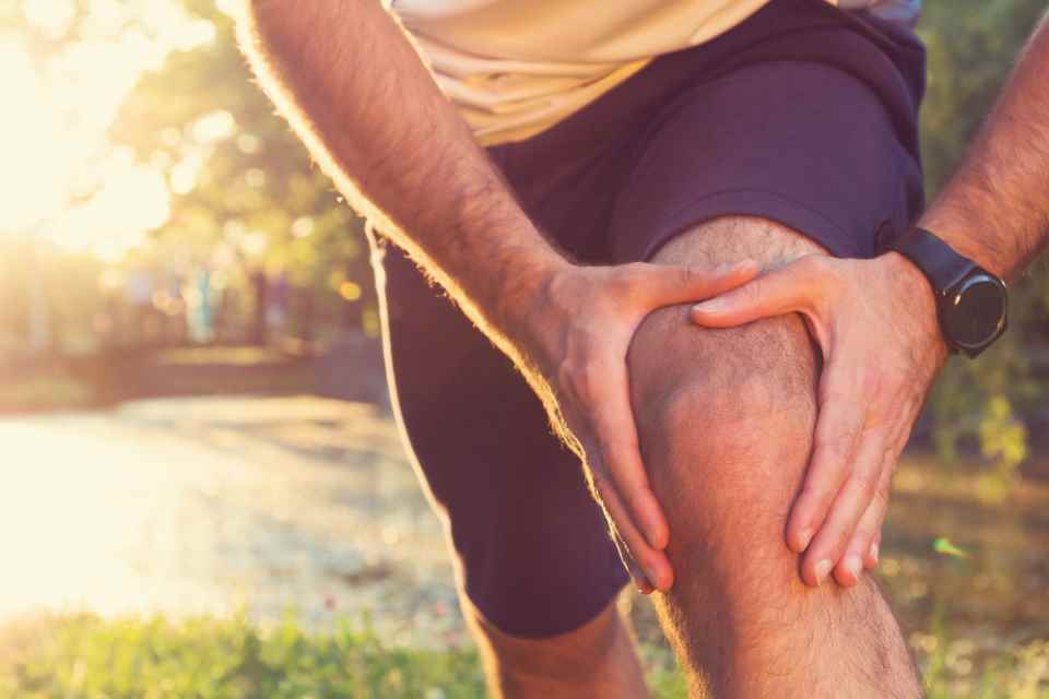 Stock picture of runner holding sore knee