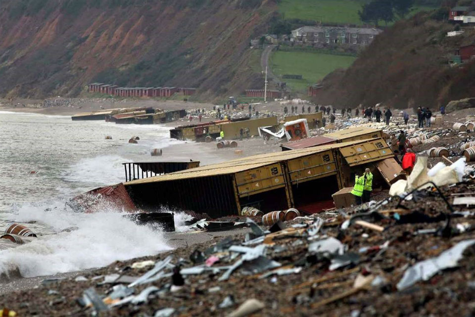Crowds of people on shore among dozens of containers washed up