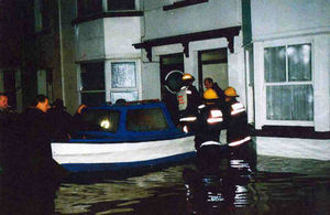 Firefighters rescue someone from their flooded house in water as high as their waists