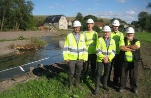 Several members of the Environment Agency next to a river with their arms crossed