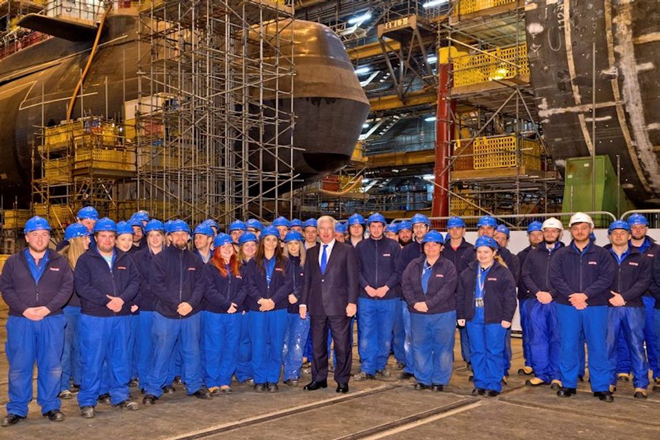 Defence Secretary Sir Michael Fallon with BAE Systems apprentices inside Devonshire Dock Hall where HMS Agamemnon is under construction.