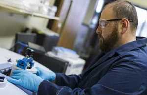 Laboratory scientist sitting and working with specialist equipment.