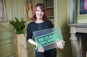 Arlene Phillips holding the Be Clear on Cancer logo.