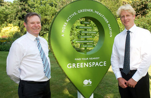Phillip Wyndham and Jo Johnson standing by a giant map pin marking a green space.