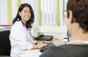 Smiling doctor looks at patient as she types on keyboard