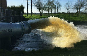 A large amount of water flying out the end of a big pipe into a river