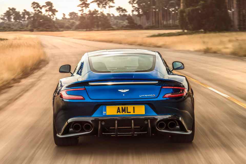 Rear view of an Aston Martin Vanquish V12 on a dusty outback road.
