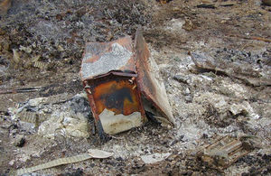 Stock image of land covered in ash and a severely burned refrigerator