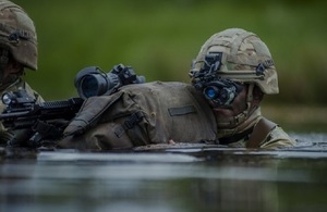Soldier in a stream using high tech vision attachment to helmet