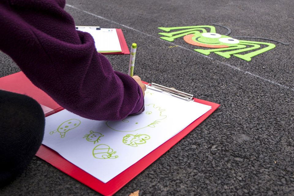 A child drawing one of the new playground decorations on a clipboard