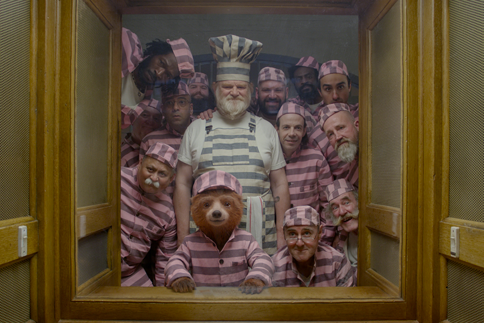 Still from Paddington 2 showing Paddington bear surrounded by the rest of the cast