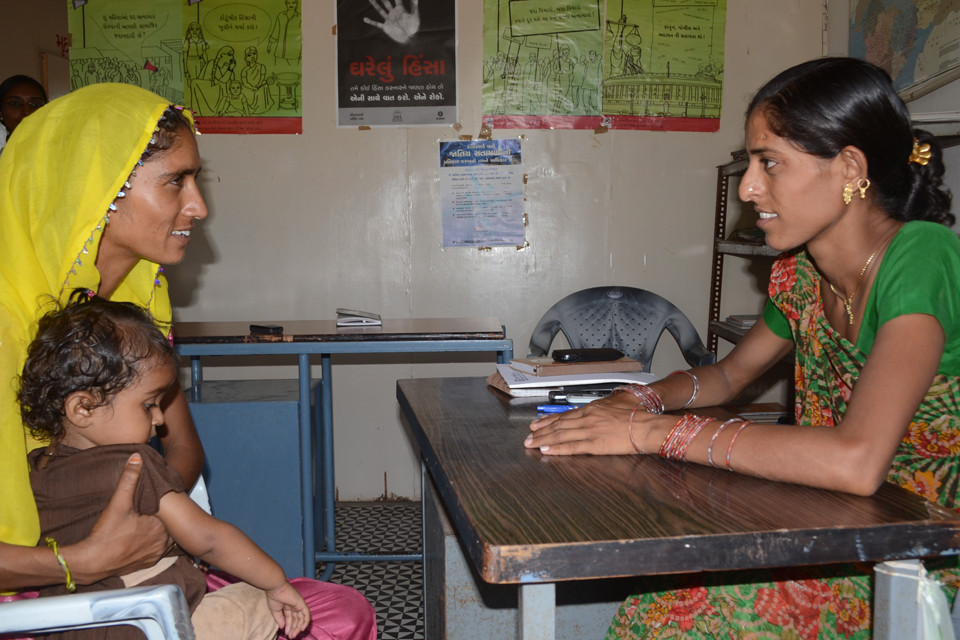 2 women sit at a table, one of them is holding a small child. Picture: Jyoti Patil