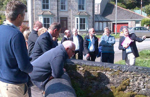 Members of the committee stood on a bridge in a village looking at the river