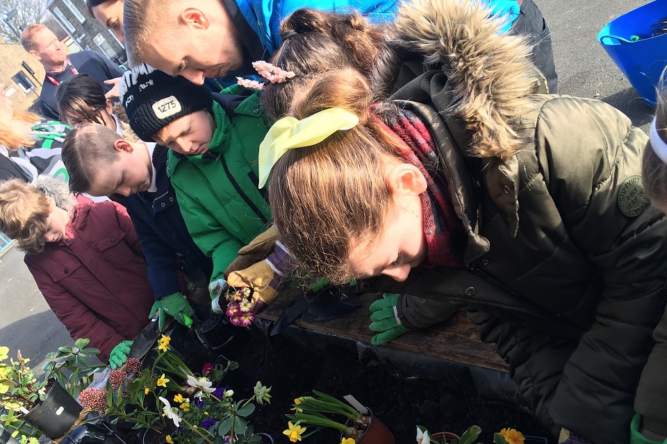 Image shows youngsters at the school putting flowers in the new rain planter