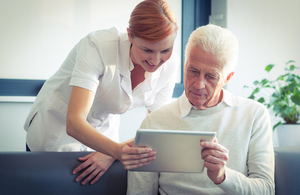 Nurse showing patient health data on tablet.