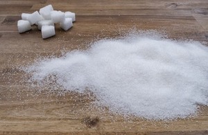 A pile of sugar cubes and granules on a wooden surface.