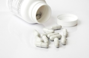 pill bottle with white capsules on a white surface