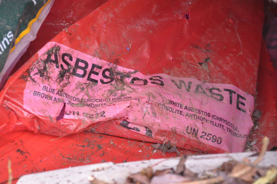 Close-up of red plastic waste bag with asbestos written on it