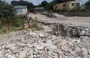 A quarry-like site with industrial shed and broken rocks littering the road