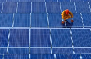 A technician works on solar panels via W Joke khumkhur at Shutterstock