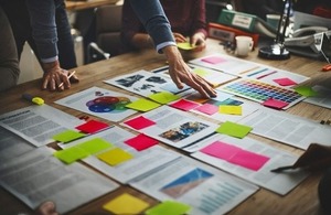 Business team work around a desk of papers via Rawpixel.com at Shutterstock