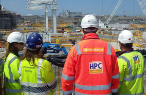 People in hard hats wearing Environment Agency and HPC jackets watching construction of Hinkley Point C
