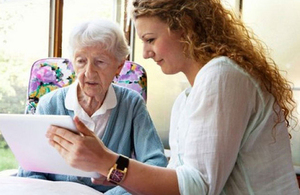 Woman showing an older woman a digital tablet.