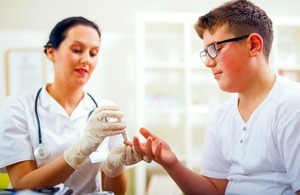 Health professional measures a patient's glucose level using glucometer via adriaticfoto at Shutterstock