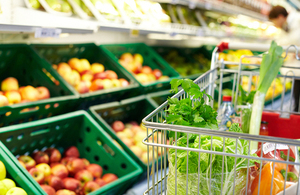 A shopping trolley with food inside it, in a supermarket.