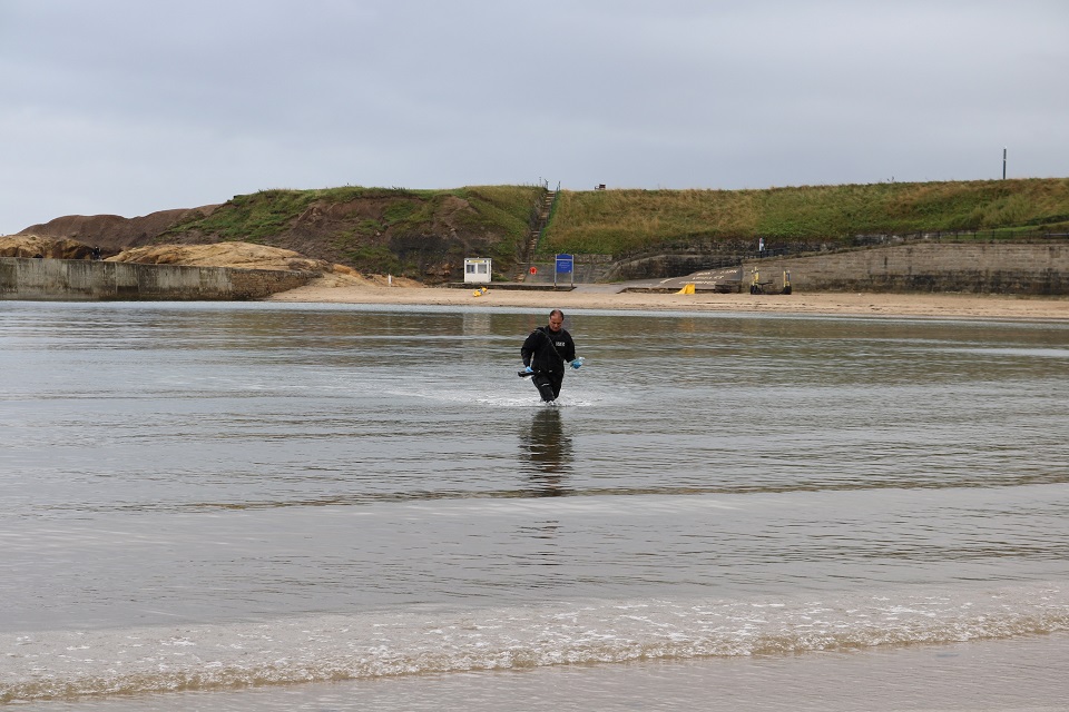 The image shows the Environment Agency's Mick Donkin collecting samples at Cullercoats 