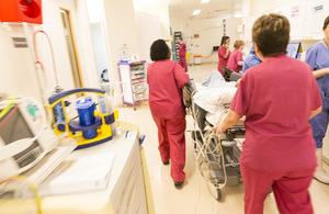 Nurses wheeling a patient through a ward.