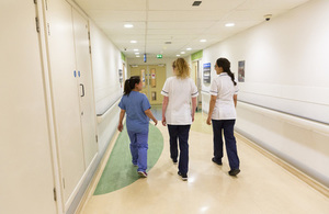 Three nurses walking away down a hospital corridor
