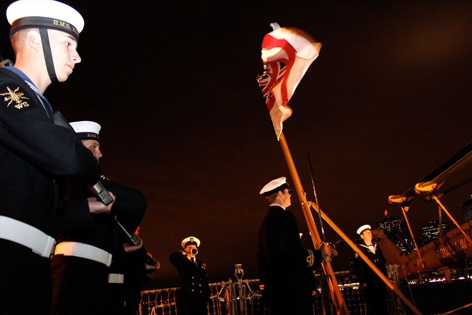 The crew of the HMS Edinburgh lower the flag at sunset.