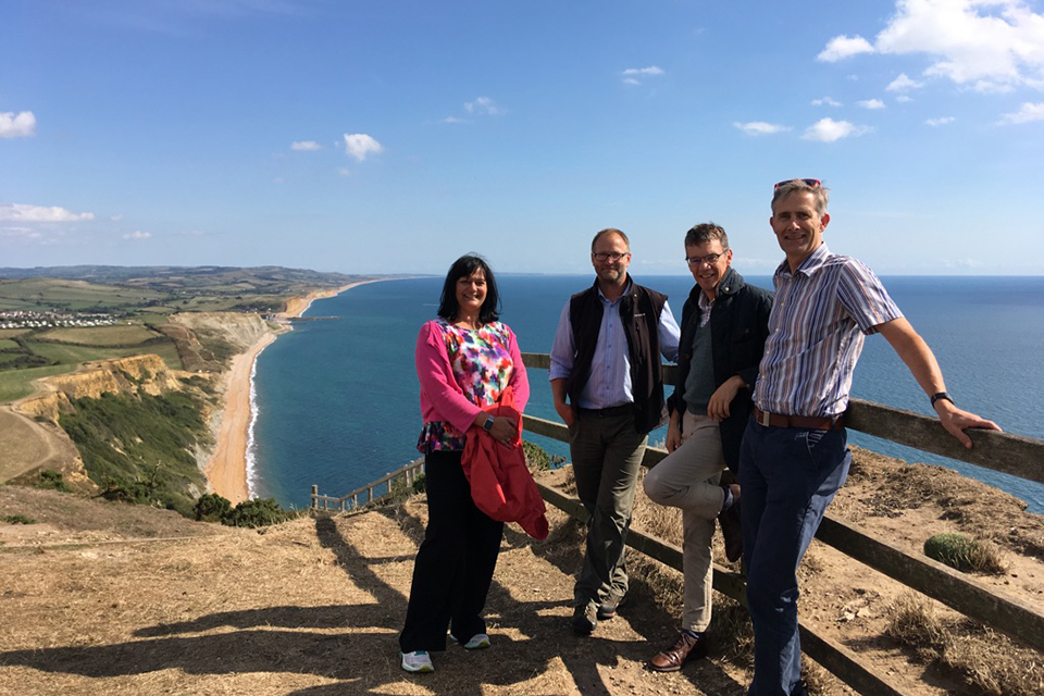Picture of the review panel leaning against a fence on a cliff edge overlooking the sea