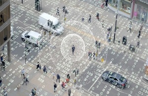 A city square with cars and people with an overlay of transparent data
