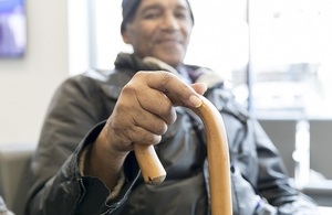 An elderly man with a walking stick, smiling.