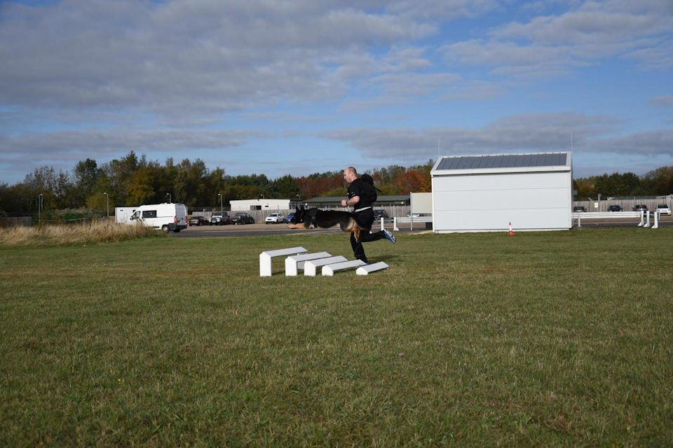 Ministry of Defence policeman jumping high over the hurdles.