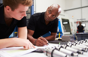 Stock image of an apprentice being helped with their work.