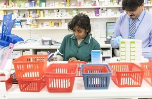 Pharmacist working behind the counter with baskets of medicines.