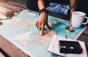 Tourist planning a trip using a world map via Jacob Lund at Shutterstock
